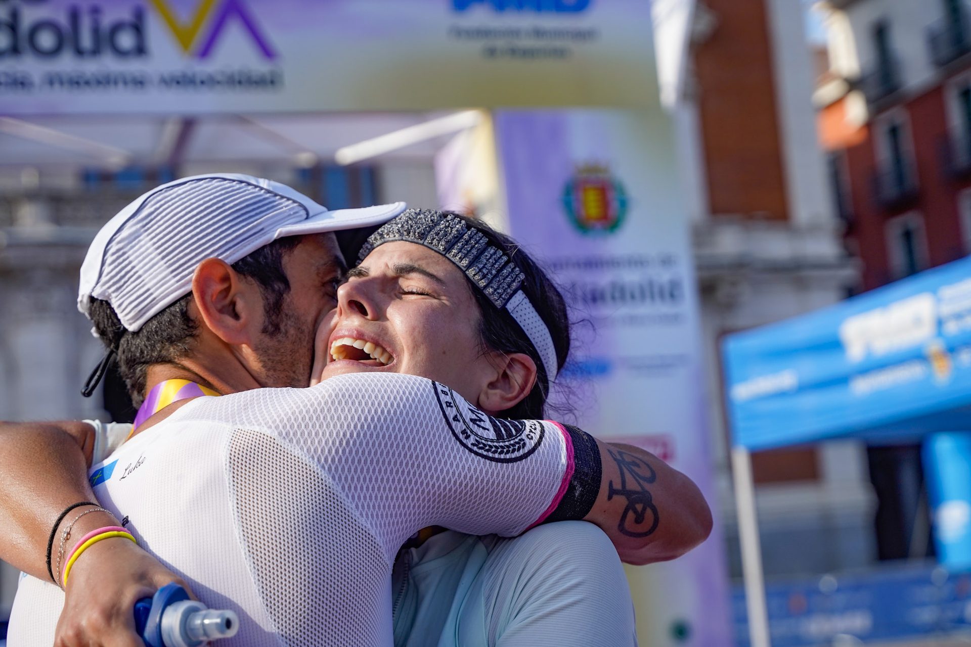 Dos triatletas se abrazan emocionados en el arco de meta